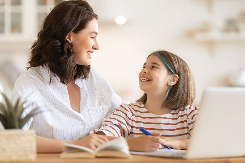 Back to school. Happy child and adult are sitting at desk