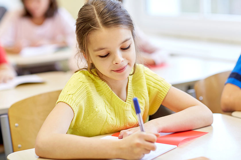 Group of school kids writing test in classroom